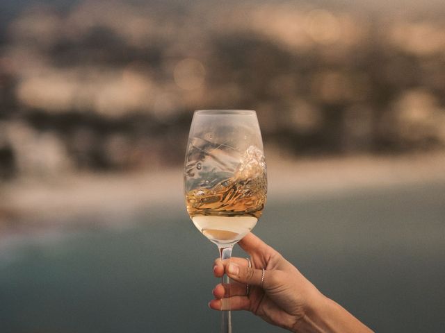 A glass of white wine held up against the Cape coastline at dusk