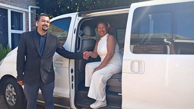 Andre, your driver, smiling beside the white Hyundai H1, holding the hand of a smiling passenger seated in the open door